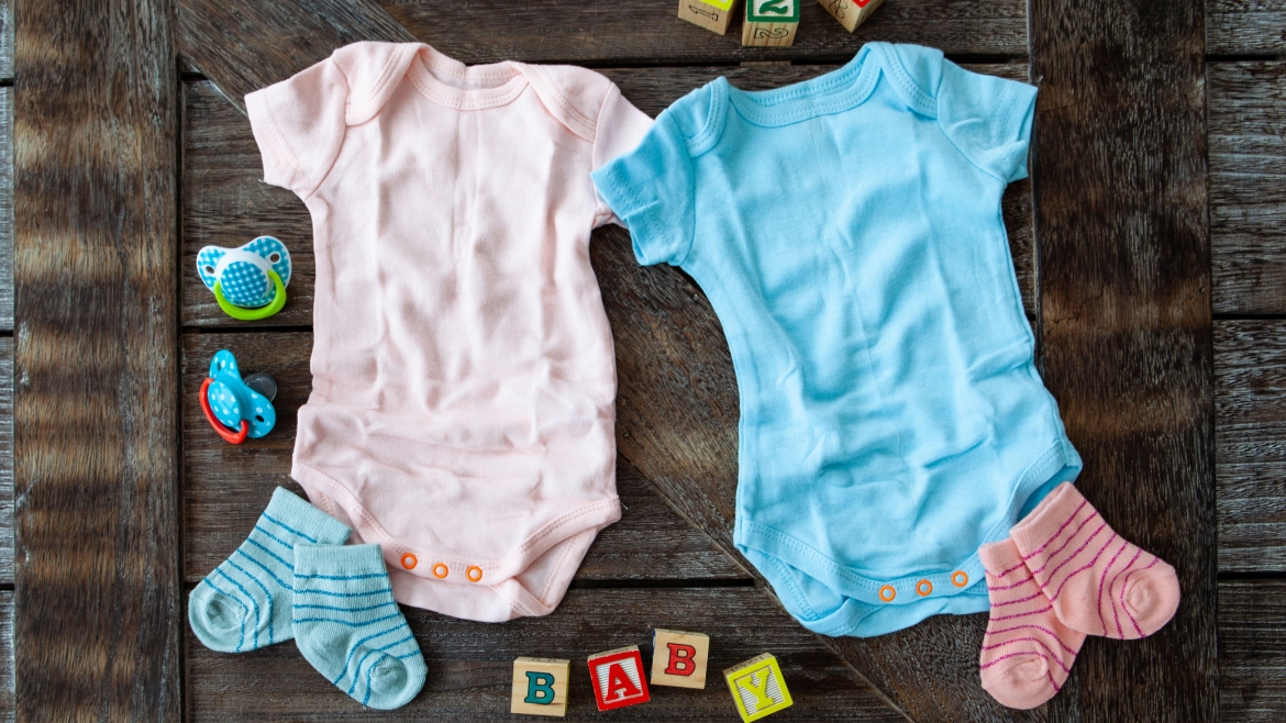 Baby clothing in pink and blue on rustic wooden background