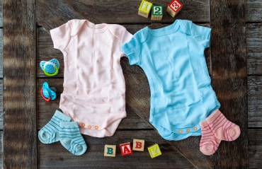 Baby clothing in pink and blue on rustic wooden background