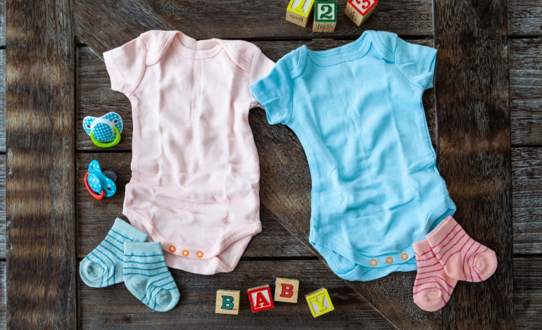 Baby clothing in pink and blue on rustic wooden background