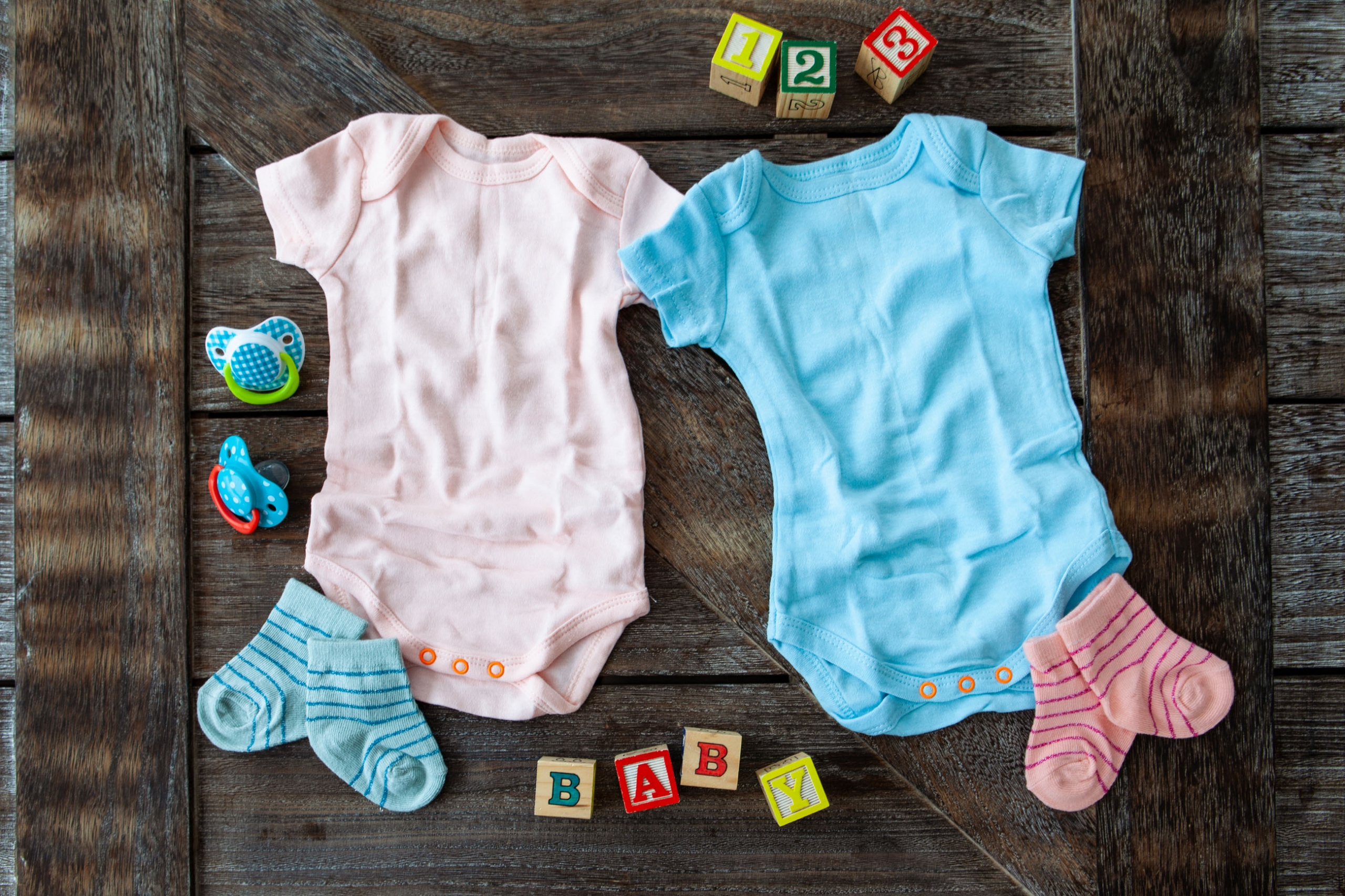 Baby clothing in pink and blue on rustic wooden background